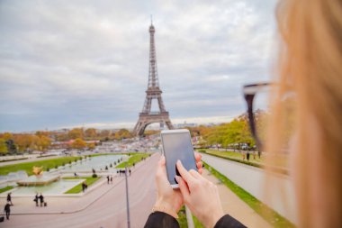 Paris geçmişi ve Eyfel kulesi olan cep telefonu kullanan bir kız..