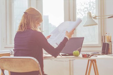 Parlak güneşli oda bir projede çalışan kadın mimar.