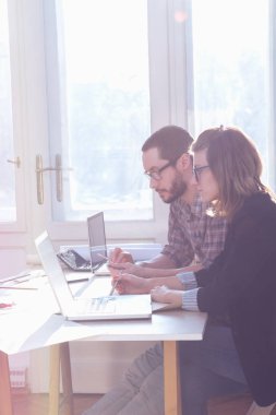 Gençler güneşli ofiste bir proje üzerinde çalışıyor.