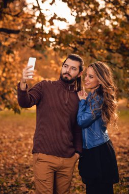 Genç çift sonbahar renkli park'cep telefonu kullanma.