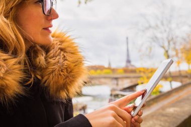 Paris geçmişi ve Eyfel kulesi olan cep telefonu kullanan bir kız..