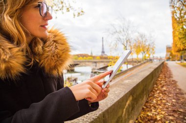 Paris geçmişi ve Eyfel kulesi olan cep telefonu kullanan bir kız..