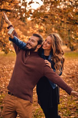 Genç çift sonbahar renkli park'cep telefonu kullanma.