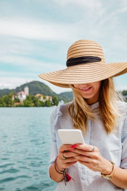 Smartphone kullanarak göl kenarında şirin kız.