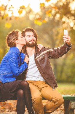 Genç çift sonbahar renkli park'cep telefonu kullanma.