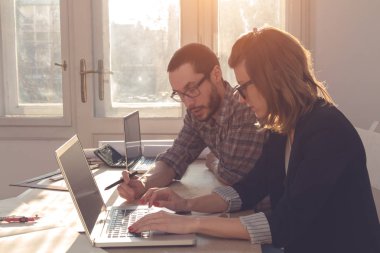 Gençler güneşli ofiste bir proje üzerinde çalışıyor.