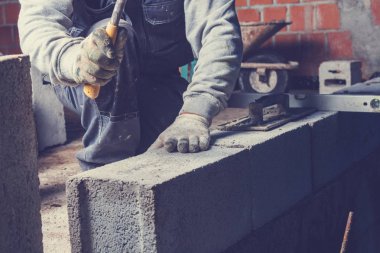 Gerçek inşaat işçisi aletleri kullanarak duvarı örüyor..