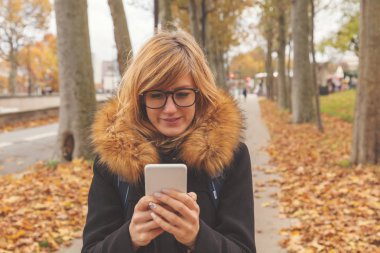 Sevimli kız sokakta cep telefonu kullanarak.