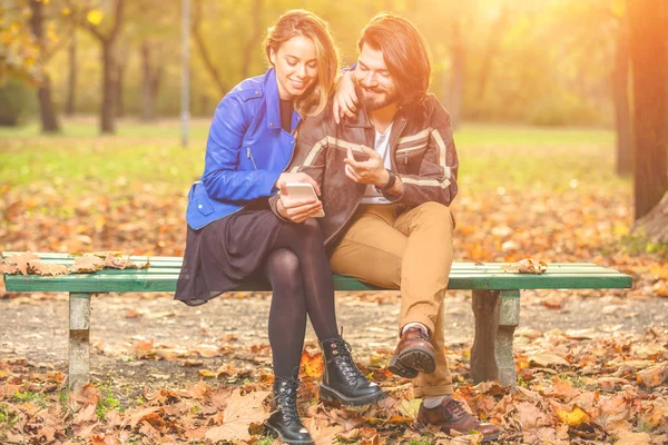 Casal Jovem Usando Celular Outono Colorido Parque — Fotografia de Stock