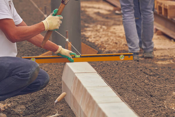 Настоящий строитель с измерительной лентой выравнивания бетонных блоков
.