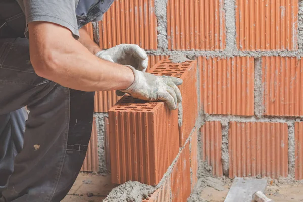 Real construction worker bricklaying the wall indoors.