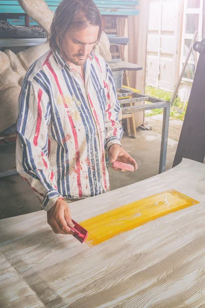 Artist using tool for making artificial wood texture.