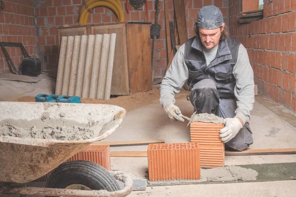 Real construction worker bricklaying the wall indoors.