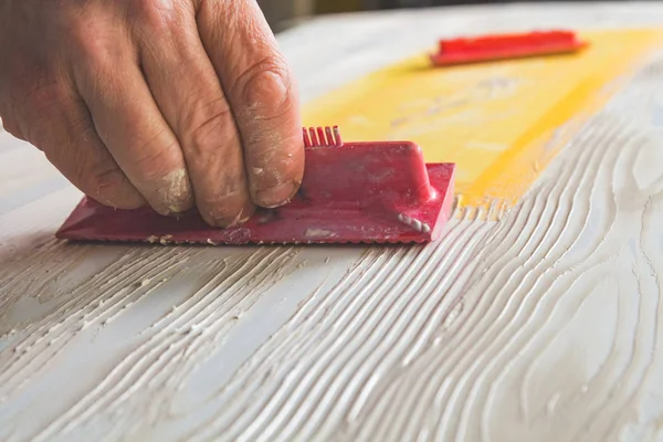 Artist using tool for making artificial wood texture.