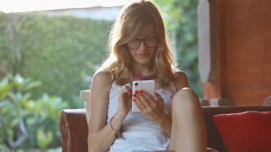 Teras koltukta oturan smartphone kullanan kadın