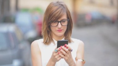 Beyaz bluz smartphone kullanarak kadın kentsel arka plan bulanık