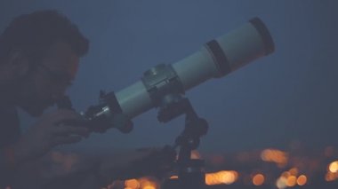 Ayarlama ve astronomik teleskop akşam arayan genç adam.