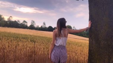 Genç kadın arasında buğday olgunlaşma alanı ağacında, poz