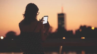 Açık, akıllı telefon kullanan genç kadın arka plan nehirde köprüden.