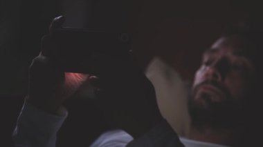 Sakallı adam gece kanepede döşenmesi smartphone kullanarak