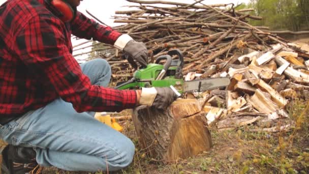 Skogshuggare Med Motorsåg Och Högen Skurna Woods — Stockvideo