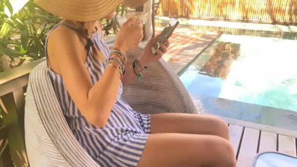 Genç Kadın Elbise Şapka Manifatura Smartphone Kullanarak Havuz Kenarında Çay — Stok video
