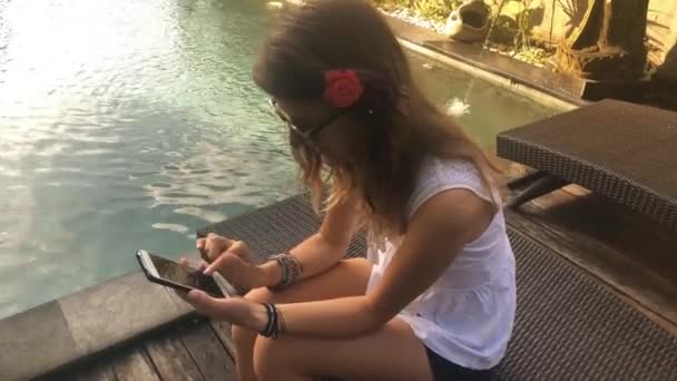 Jeune femme textos à des amis en utilisant smartphone à la piscine 