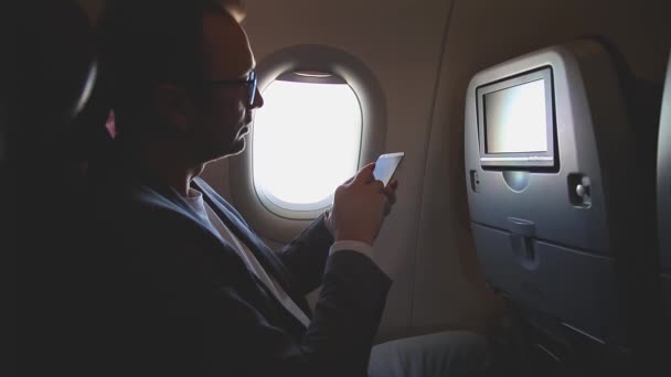 Hombre Usando Smartphone Viajando Avión — Vídeo de stock