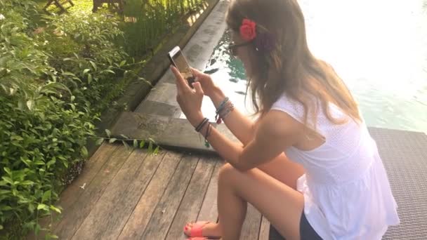 Νεαρή Γυναίκα Γραπτών Μηνυμάτων Στους Φίλους Χρησιμοποιώντας Smartphone Στην Πισίνα — Αρχείο Βίντεο
