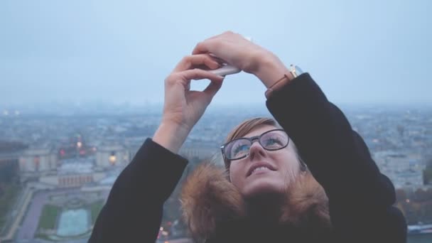 ビデオを作るメガネの女性都市背景をぼかした写真のスマート フォンを使用してください — ストック動画