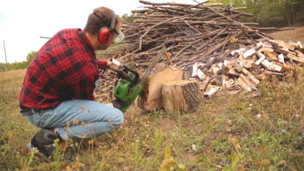 Skogshuggare Med Motorsåg Och Högen Skurna Woods — Stockvideo