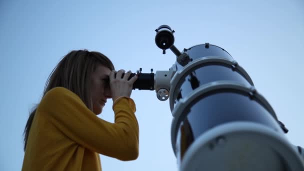 若い女性が夜の空に天体望遠鏡を通して見る — ストック動画