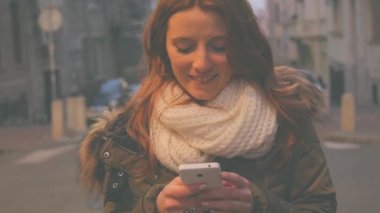 Sevimli genç kadın Smartphone kullanarak kentsel arka plan bulanık