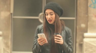 Genç esmer kadın smartphone kullanarak kırmızı ruj ve bere şapka ile şehir arka plan bulanık