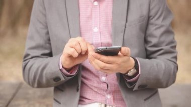 Genç adam manifatura mesaj ile smartphone Sonbahar Park görünümünü kırpılmış