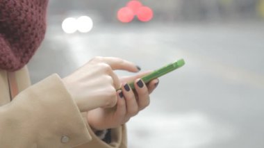 Bokeh bulanık şehir zemin üzerine Smartphone kullanan kadın.