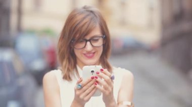 Beyaz bluz smartphone kullanarak kadın kentsel arka plan bulanık