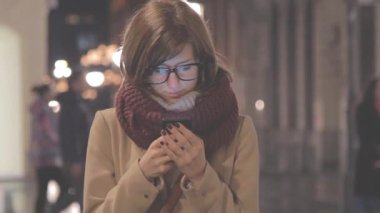 Kadın ceket ve bokeh ile kentsel arka plan bulanık smartphone kullanarak kurdele