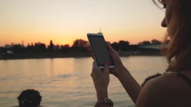 Açık, akıllı telefon kullanan genç kadın arka plan nehirde köprüden.