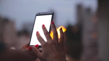 Akşam bulanık şehir arka plan üzerinde akıllı telefon kullanan genç kadın