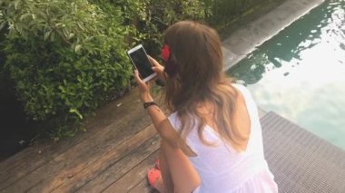 Genç kadın manifatura havuzda smartphone kullanarak arkadaşlar