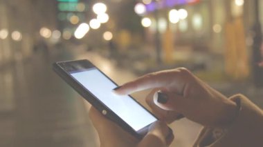 Bokeh bulanık şehir zemin üzerine Smartphone kullanan kadın.