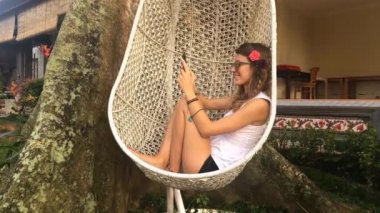 Koltuk asılı oturan smartphone kullanan genç kadın