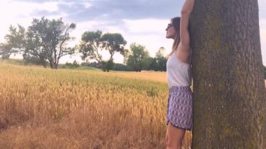 Genç kadın arasında buğday olgunlaşma alanı ağacında, poz