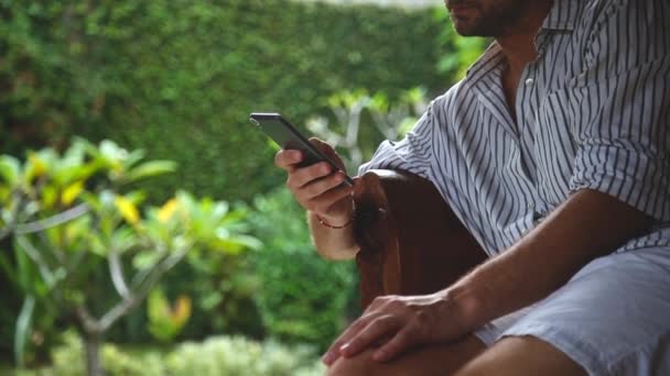 Mann Sitzt Auf Einem Terrassensofa Und Benutzt Handy — Stockvideo