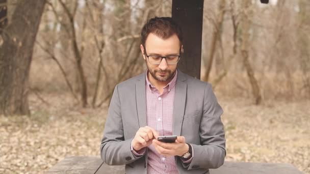 Ung Man Sms Meddelande Med Smartphone Höstlig Park — Stockvideo