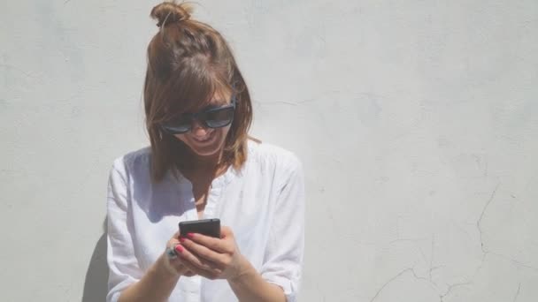 Femme Avec Chignon Lunettes Utilisant Smartphone Sur Fond Mur Blanc — Video