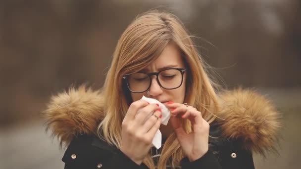 眼鏡頭痛を感じ 公園でくしゃみの若い女性 — ストック動画