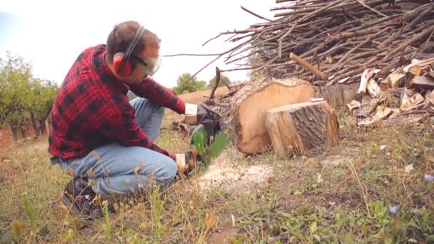 Skogshuggare Med Motorsåg Och Högen Skurna Woods — Stockvideo