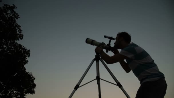 若い男を調整して 夜に天体望遠鏡を通して見る — ストック動画